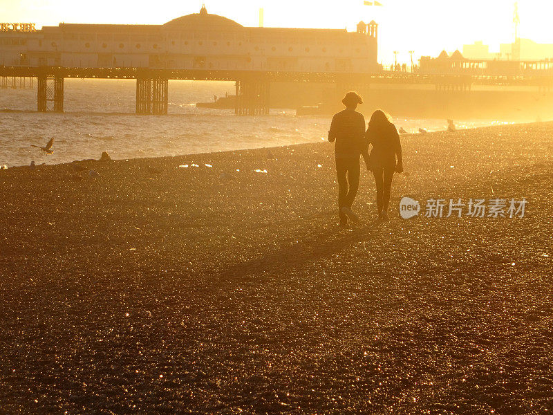 男孩/女孩在日落时分走在布莱顿海滩上